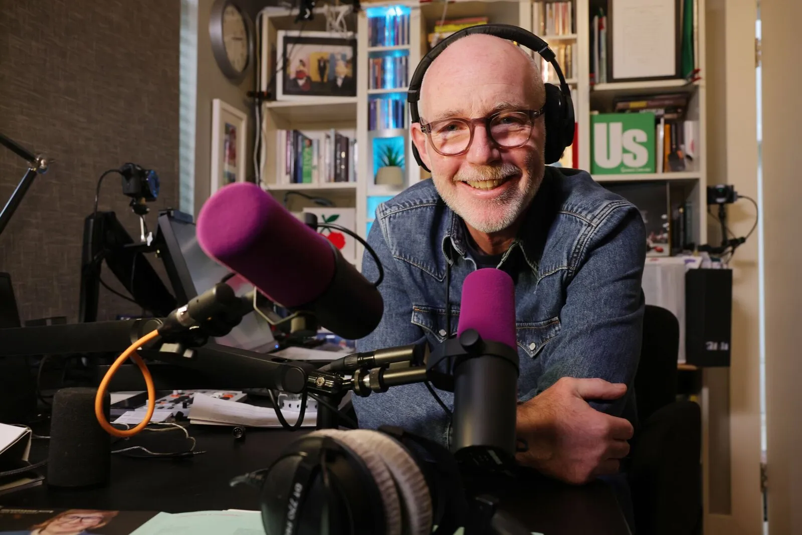 Ray D'Arcy at his desk in the studio, headphones on, two microphones in front of him.